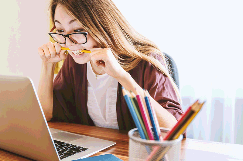 a woman biting a pencil while doing homework